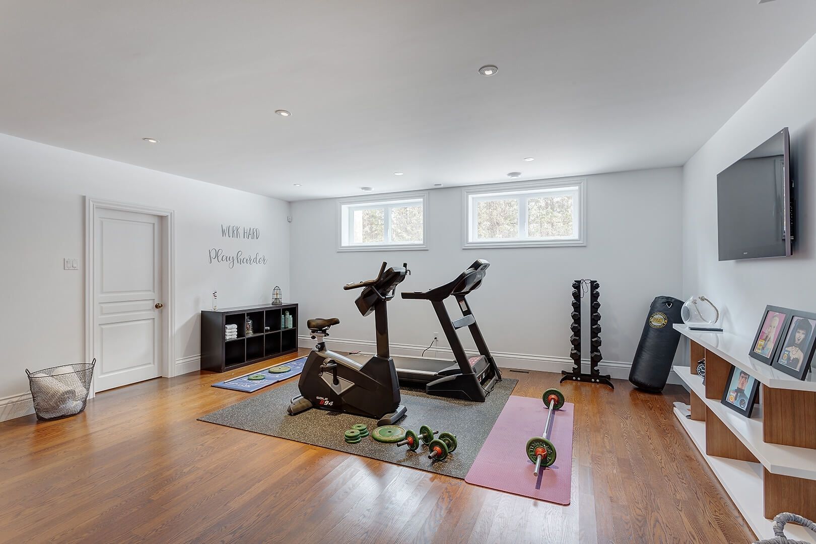 Finished basement home gym with cardio machines, free weights, and workout area.